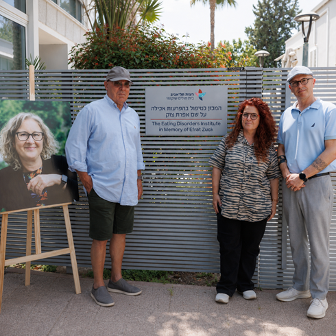 In a moving gesture by her family, the Institute for Treatment of Eating Disorders at Reuth TLV Rehabilitation Hospital will be named after Efrat Tzuk, one of the institute’s veteran staff members, who passed away several months ago. This is made possible thanks to a $100,000 donation from her family to preserve and commemorate her legacy. Efrat Tzuk was one of the institute’s most veteran professionals and served as its Chief Dietitian. The hospital’s Institute for Treatment of Eating Disorders is among the leading centers in Israel for the treatment of the population over age 18, and specializes in various types of eating disorders: anorexia, bulimia, and binge eating disorder, within the framework of intensive day treatment or outpatient care. The institute offers a multidisciplinary umbrella of care that includes, among other things, nutritional monitoring and treatment, close nursing support, psychiatric treatment, psychological treatment, dietitian-led group therapy, and psychotherapy. The moving unveiling ceremony was attended by representatives of the hospital’s management and the Reuth Association, the institute’s staff, her family, and those who cherish her memory. During the event, remarks in her memory were delivered by her team colleagues, her family, and management representatives. Erez Tzuk, Efrat’s husband, shared: "There are moments for which it is hard to find words, and one such moment is when a person’s name becomes a sign on a wall — a permanent mark that will remain. I want to thank the Reuth Association, the hospital, and the institute’s staff for seeing fit to honor her and us in this way. I know how much she loved this place and how strongly she believed in its mission. I hope that her name on the wall will remind everyone that there is a history of compassion here that continues on”. Dr. Orit Stein Reisner, Director of the Hospital, said: "Efrat was a dominant, influential force in shaping both the institute’s professional direction and its family-like character. In our meetings, I was struck by her deep familiarity with every patient and by her rare degree of care. The workplace was a significant part of who she was, and she led groundbreaking therapeutic initiatives”. Ido Sharir, CEO of the Reuth Association, said: "The hospital is focused on giving and acting for the sake of others at the most critical junctures of their lives. The Tzuk family’s decision to commemorate Efrat in this way is deeply meaningful, and it strengthens our connection as an organization to our employees and their families. Efrat’s memory will continue to accompany us going forward, and we thank her family for this deeply moving choice”. Amir Zendakovich, Director of the Institute for Treatment of Eating Disorders and Head of the Psychological Services Division, spoke about how much Efrat is missed: "We miss Efrat. She was an outstanding professional — sharp, incisive, with a deep sense of belonging and responsibility toward the team, and above all, sound common sense. For her, teamwork and therapeutic work were an extension of parental responsibility, compassion, boundaries, and genuine care. Our patients could not have changed their lives without this. To me, she was a friend and a partner, and everything I learned from her and with her stays with me every day. Our patients feel at home here, and that is exactly what she wanted — and she succeeded". Pictured: Erez Tzuk (left) alongside the hospital director and the director of the Eating Disorders Treatment Institute at the unveiling ceremony. Photo: Ilya Ryabkov